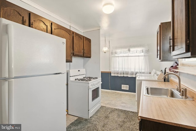 kitchen with visible vents, a sink, washing machine and dryer, white appliances, and light countertops