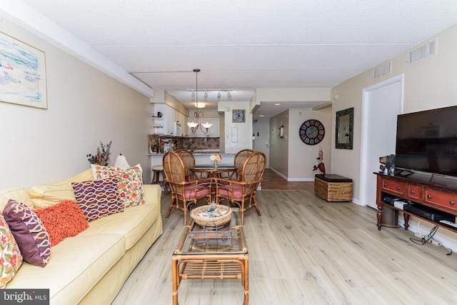 living area featuring baseboards, visible vents, and light wood-type flooring