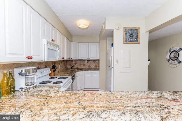 kitchen with tasteful backsplash, white cabinets, and white appliances