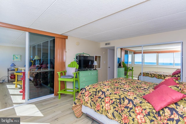 bedroom with visible vents, a textured ceiling, and wood finished floors