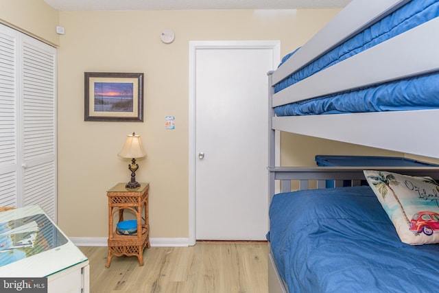 bedroom featuring a closet, baseboards, and light wood finished floors