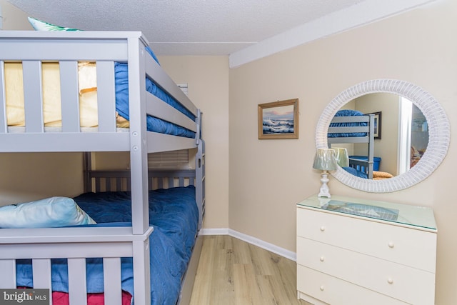 bedroom featuring baseboards, a textured ceiling, and wood finished floors