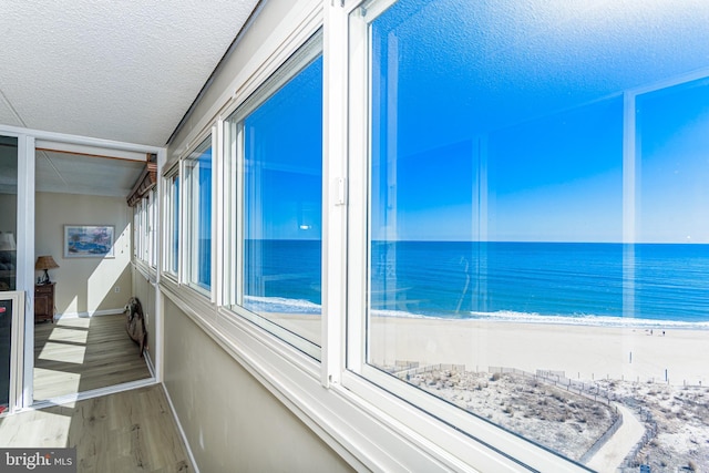 unfurnished sunroom featuring a beach view and a water view