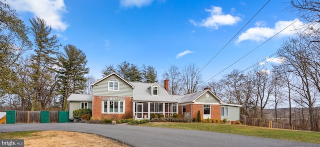 traditional-style house with a front lawn, fence, brick siding, and a chimney