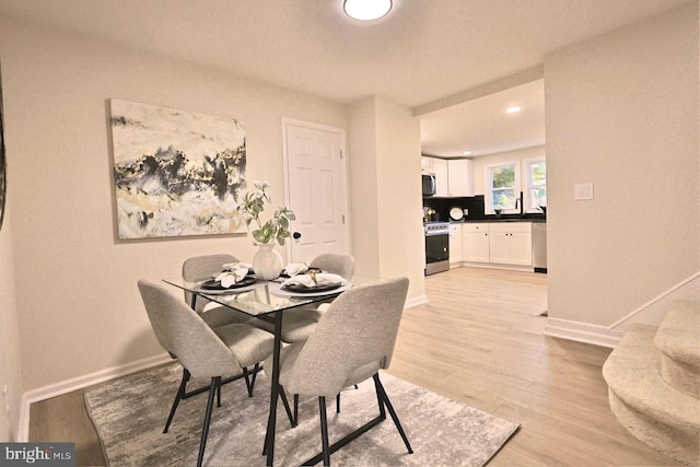 dining space with light wood-style flooring and baseboards