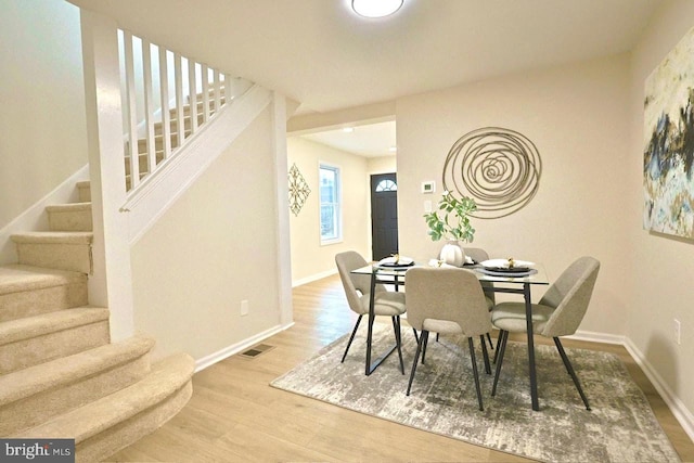 dining area featuring visible vents, stairway, wood finished floors, and baseboards