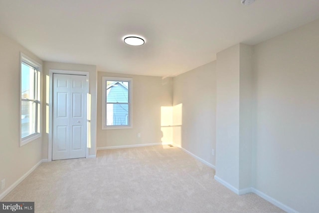 empty room with baseboards and light carpet