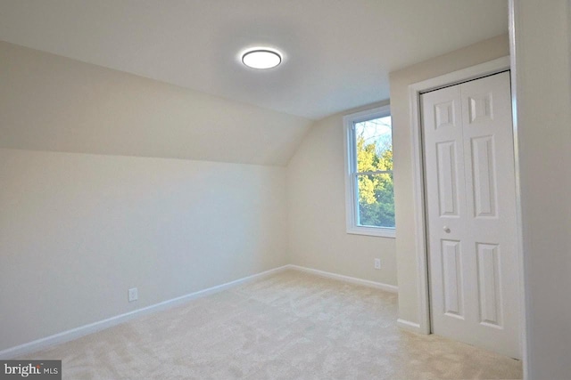 additional living space with baseboards, lofted ceiling, and light colored carpet