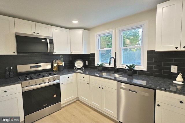 kitchen featuring a sink, appliances with stainless steel finishes, light wood-style flooring, and white cabinetry