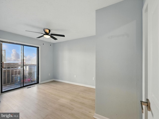 empty room with wood finished floors, visible vents, baseboards, ceiling fan, and a textured ceiling