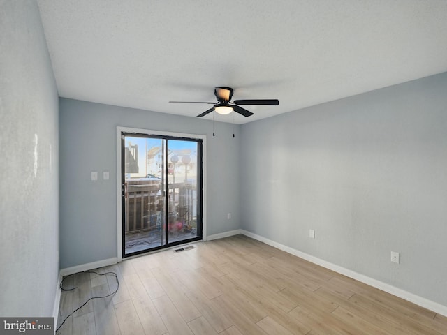 empty room featuring visible vents, ceiling fan, baseboards, and wood finished floors