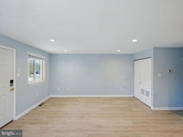 interior space featuring recessed lighting, baseboards, light wood-type flooring, and a textured ceiling