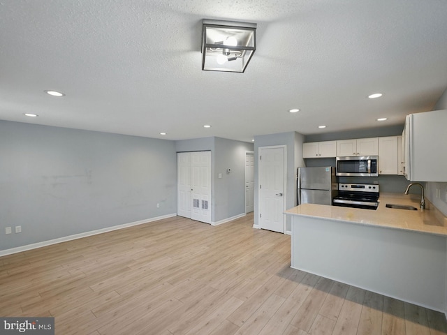 kitchen with light wood finished floors, recessed lighting, a sink, stainless steel appliances, and light countertops