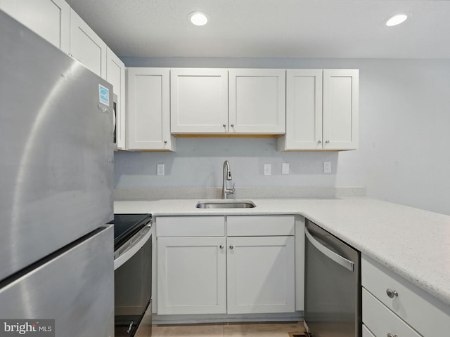 kitchen with a sink, stainless steel appliances, white cabinets, and recessed lighting