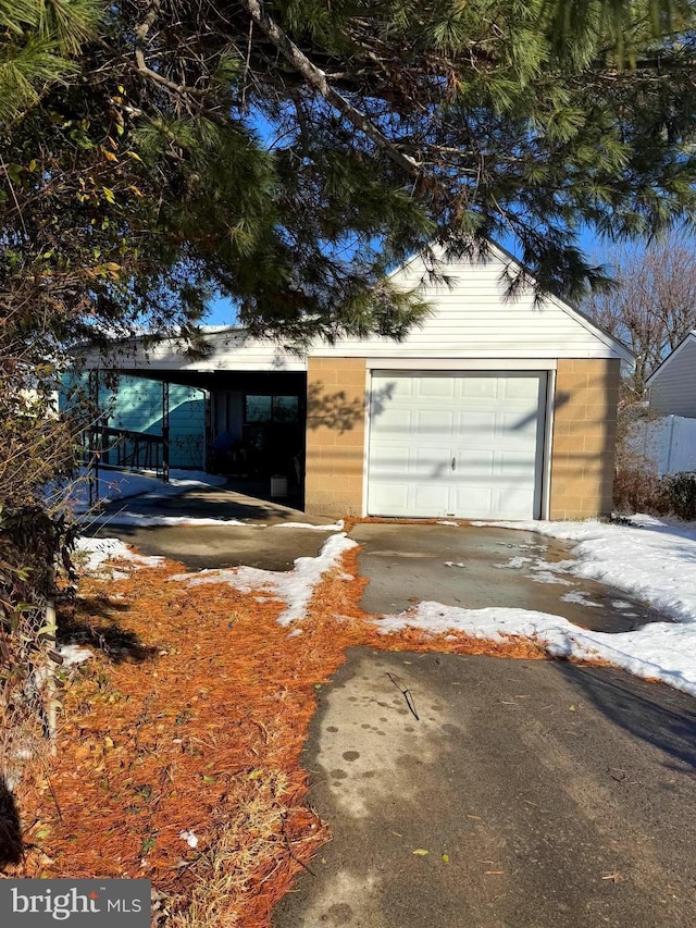 view of front of property featuring driveway, an outdoor structure, a garage, and concrete block siding