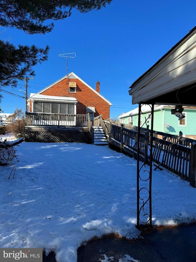 view of snow covered exterior featuring a deck and a chimney