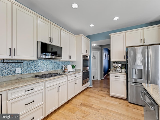 kitchen featuring light stone countertops, light wood-type flooring, recessed lighting, appliances with stainless steel finishes, and tasteful backsplash