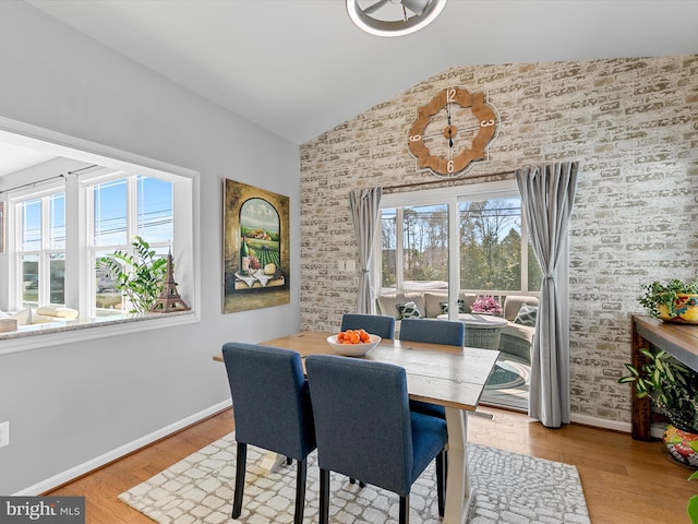 dining area with baseboards, wood finished floors, and vaulted ceiling