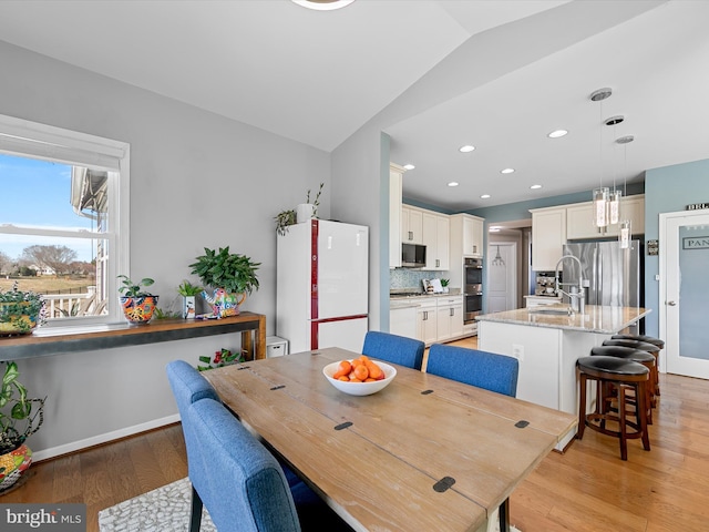 dining room featuring recessed lighting, baseboards, light wood-type flooring, and lofted ceiling