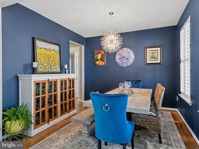 dining room with visible vents, baseboards, wood finished floors, and a chandelier