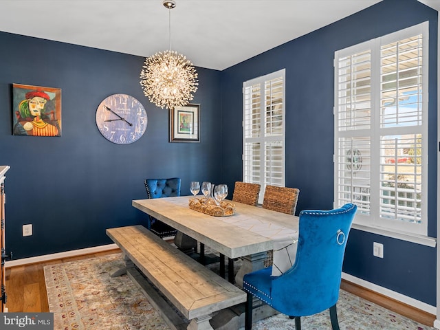 dining space with a notable chandelier, wood finished floors, and baseboards