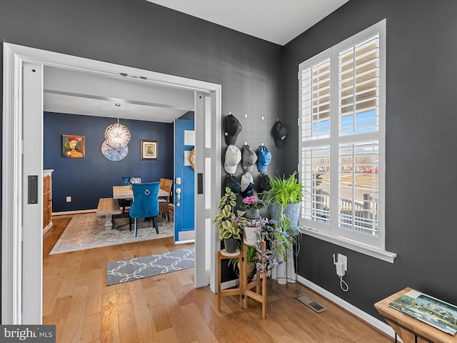 interior space with visible vents, an inviting chandelier, baseboards, and wood finished floors