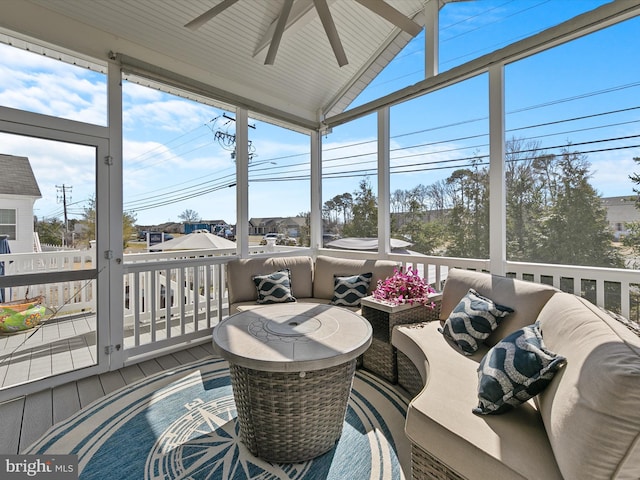 sunroom / solarium featuring lofted ceiling, a ceiling fan, and a wealth of natural light