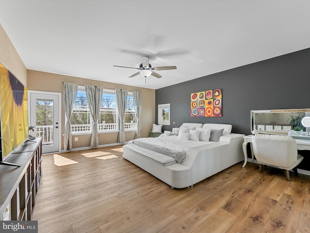 bedroom with a ceiling fan, baseboards, access to exterior, light wood-style floors, and an accent wall