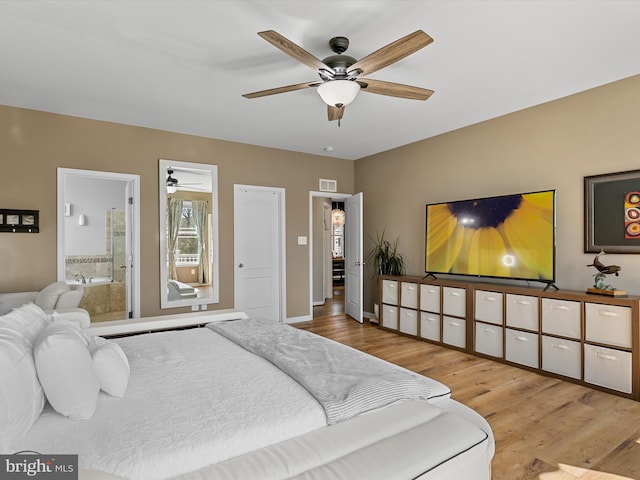 bedroom with wood finished floors, visible vents, and connected bathroom