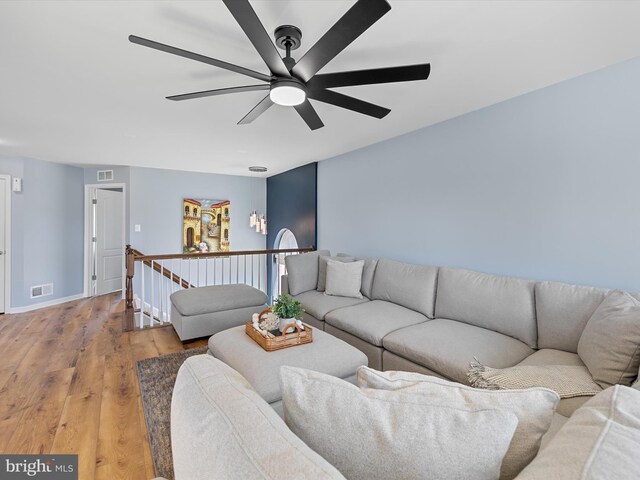 living area with a ceiling fan, baseboards, visible vents, and light wood-type flooring