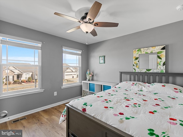 bedroom featuring visible vents, baseboards, light wood-style flooring, and a ceiling fan