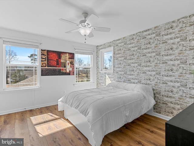 bedroom with multiple windows, baseboards, and wood finished floors