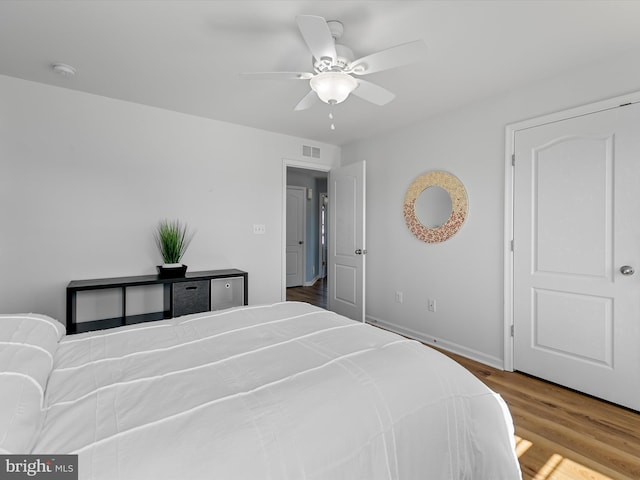 bedroom with ceiling fan, visible vents, baseboards, and wood finished floors