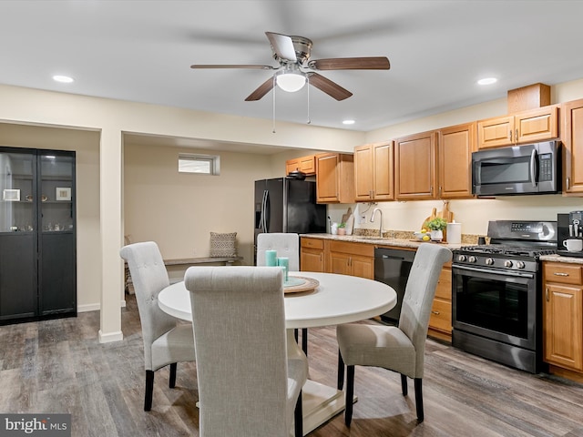 kitchen with dark wood finished floors, recessed lighting, black appliances, and a sink