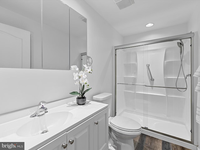 bathroom featuring visible vents, a shower stall, toilet, and wood finished floors