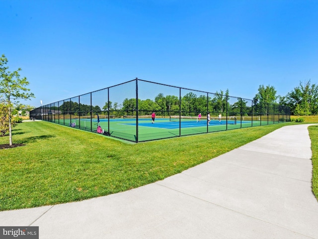 view of tennis court with fence and a lawn