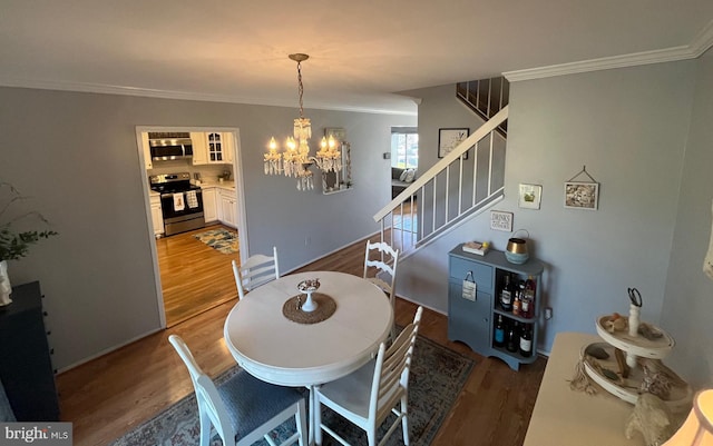 dining room with a chandelier, wood finished floors, stairs, and crown molding