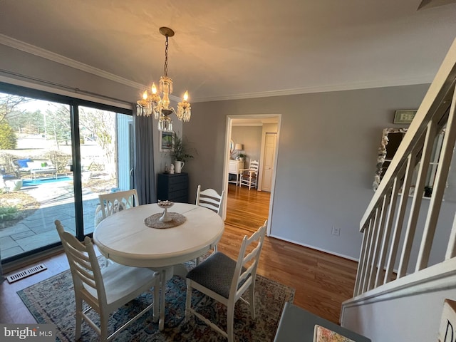 dining space with visible vents, crown molding, a chandelier, stairway, and wood finished floors