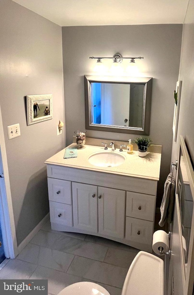 bathroom with baseboards, toilet, and vanity