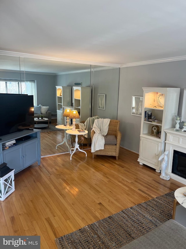 living area featuring light wood-style floors, a fireplace, and crown molding