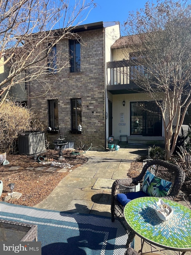 back of property featuring a patio, brick siding, and a balcony