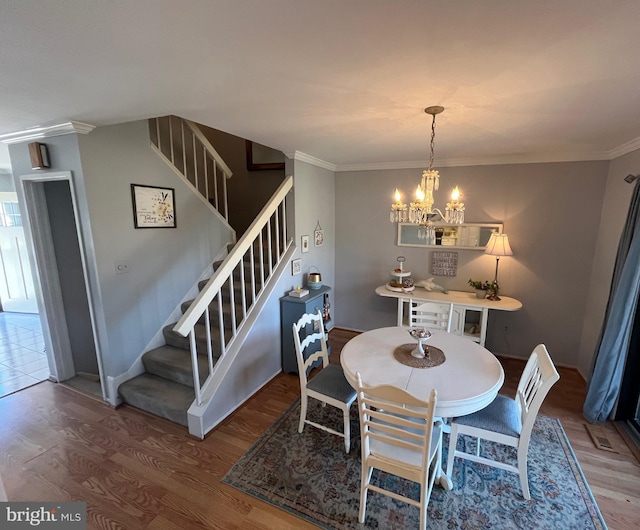 dining area featuring stairway, crown molding, an inviting chandelier, and wood finished floors