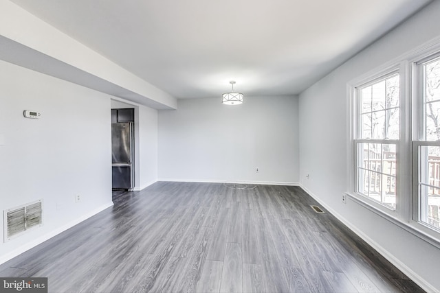 empty room featuring dark wood finished floors, visible vents, and baseboards