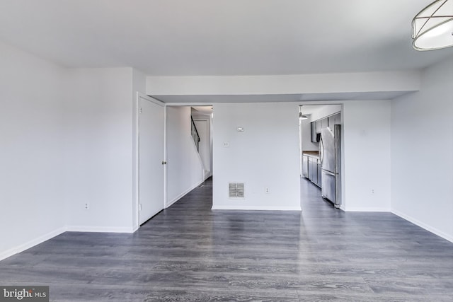 unfurnished room featuring visible vents, baseboards, and dark wood-style flooring