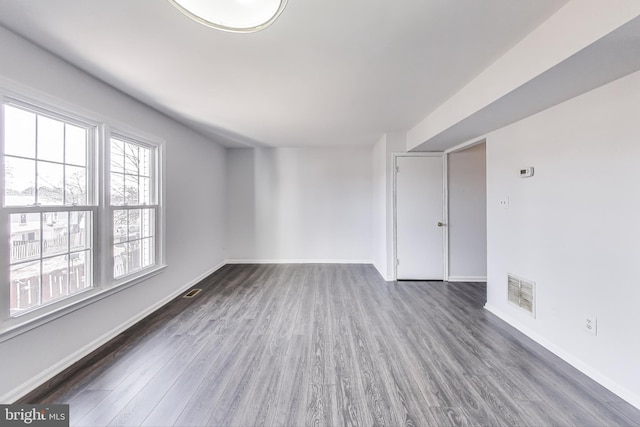 empty room featuring visible vents, baseboards, and wood finished floors