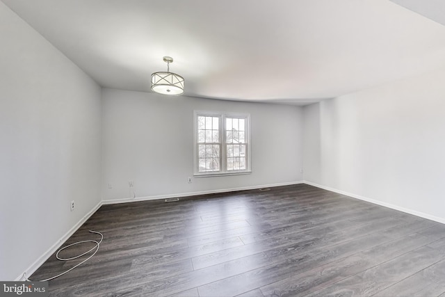 empty room featuring dark wood finished floors and baseboards