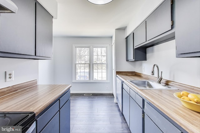 kitchen with a sink, baseboards, light countertops, white dishwasher, and dark wood-style flooring