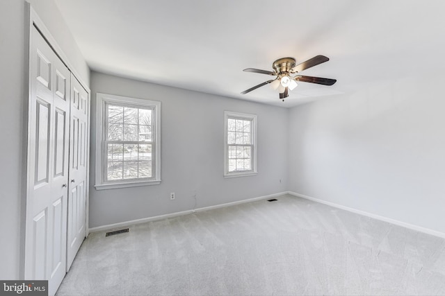 unfurnished bedroom featuring a closet, light carpet, baseboards, and visible vents