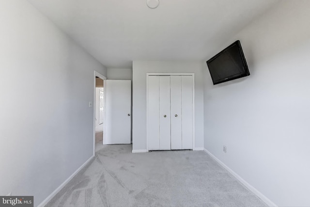 unfurnished bedroom with a closet, baseboards, and carpet flooring