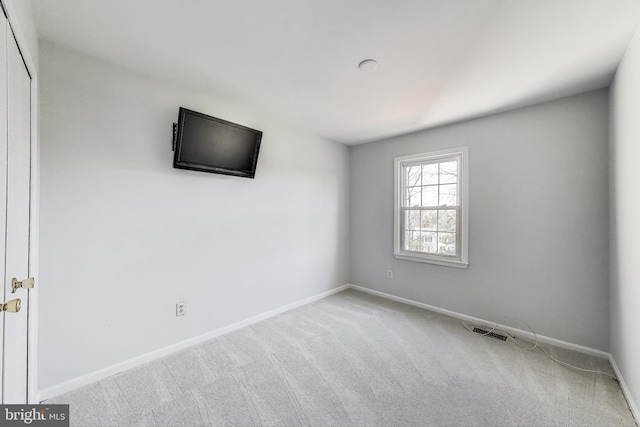 carpeted spare room with visible vents and baseboards